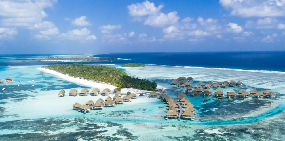 Stunning aerial view of tropical water villas and beaches in the Maldives, showcasing turquoise waters and lush islands.