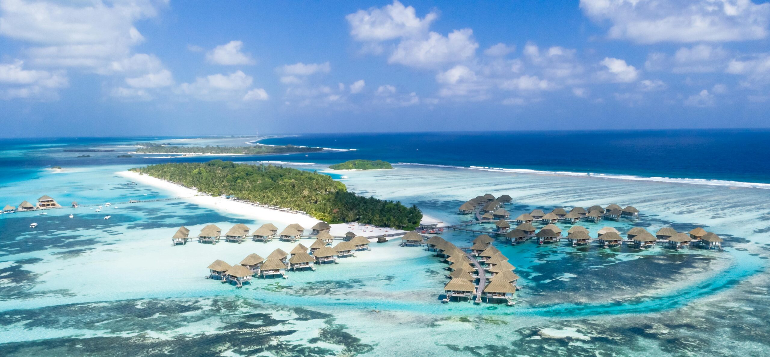 Stunning aerial view of tropical water villas and beaches in the Maldives, showcasing turquoise waters and lush islands.